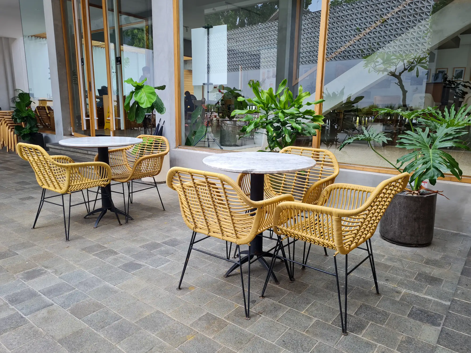 Mobilier extérieur pour professionnel : tables rondes effet marbre et chaises en rotin